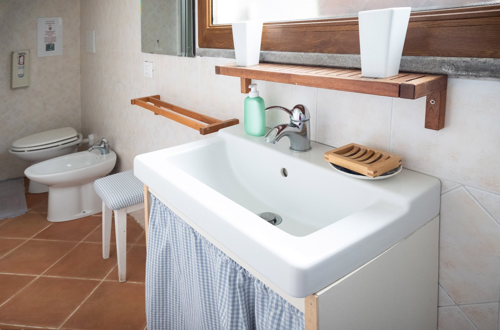bagno con lavello moderno bianco di fronte a una grande finestra lumionsa e sullo sfondo water e bidet
