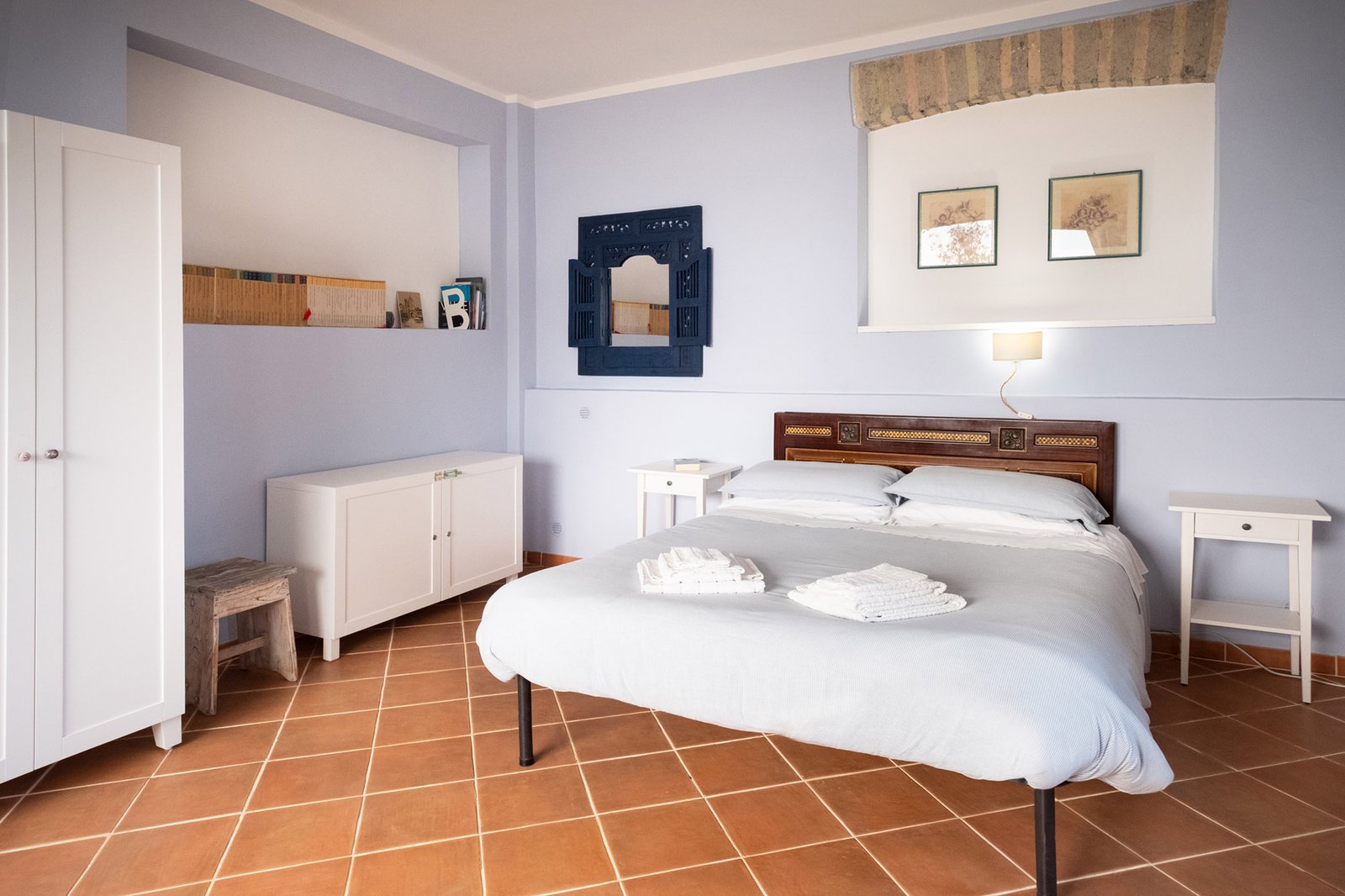 letto matrimoniale con libri sullo sfondo e specchio